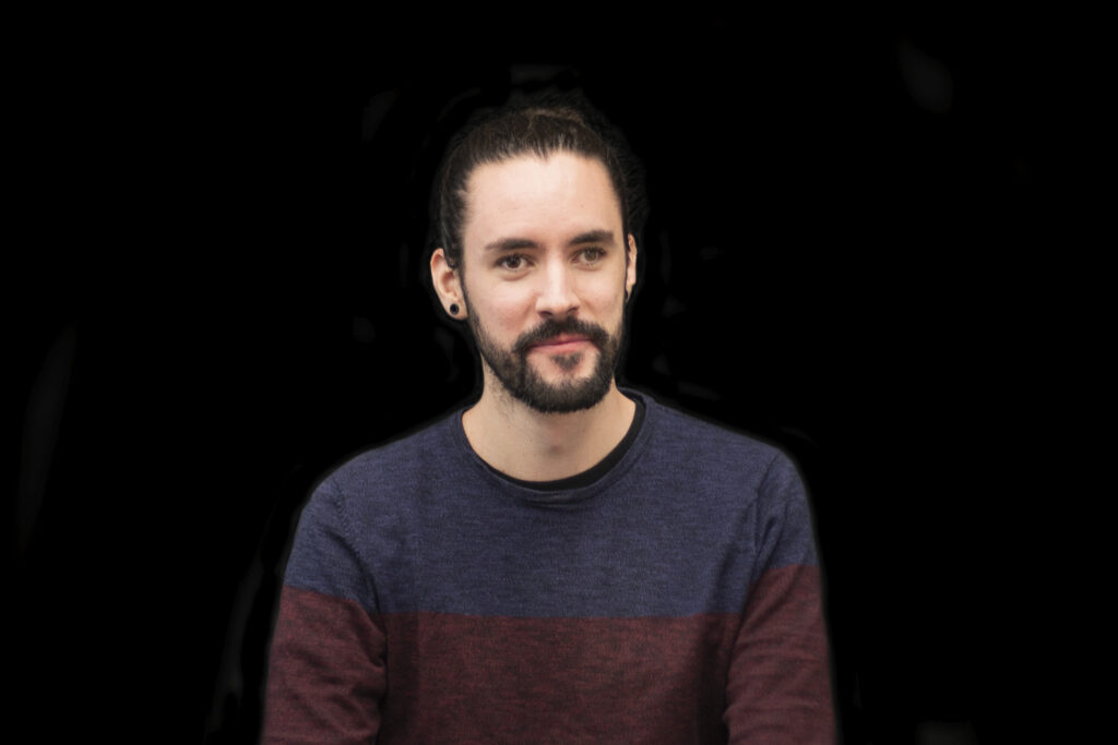 Scientist Jose Aguiar-Cervera. Black hair in a short pony-tail and a neatly cropped beard and mustache. 